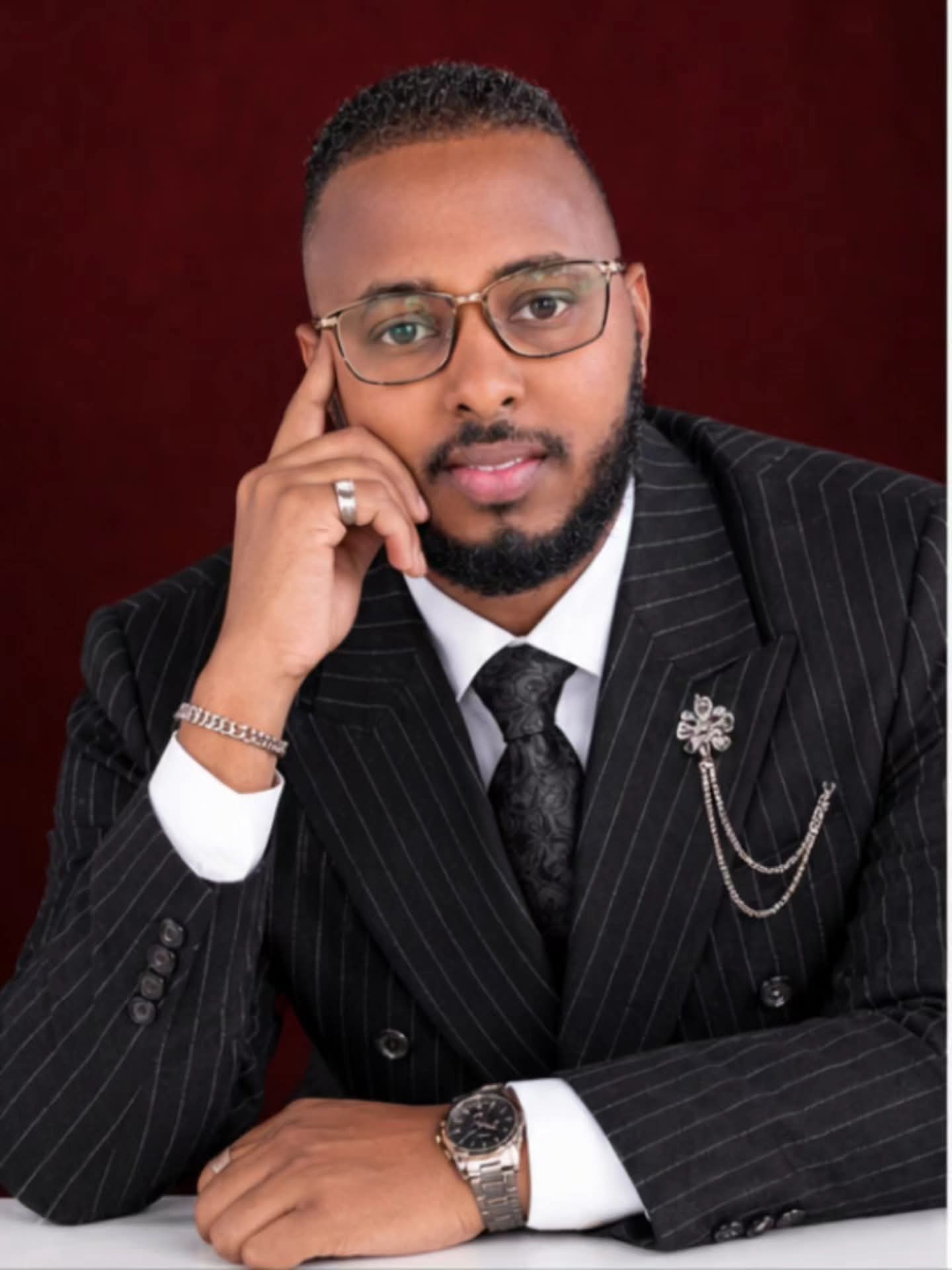 Close-up of a black pinstripe suit with a decorative lapel chain